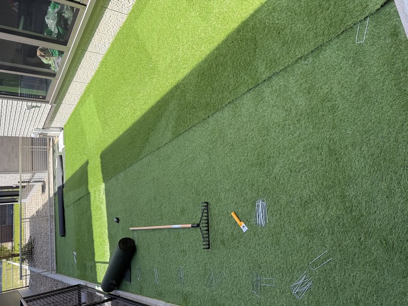 庭のドッグランをDIYで施工中。防草シートの上に人工芝を張っている様子